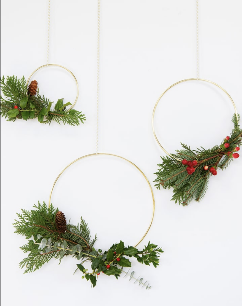 A minimalist DIY Christmas wreath with fresh greenery on a gold macrame hoop.