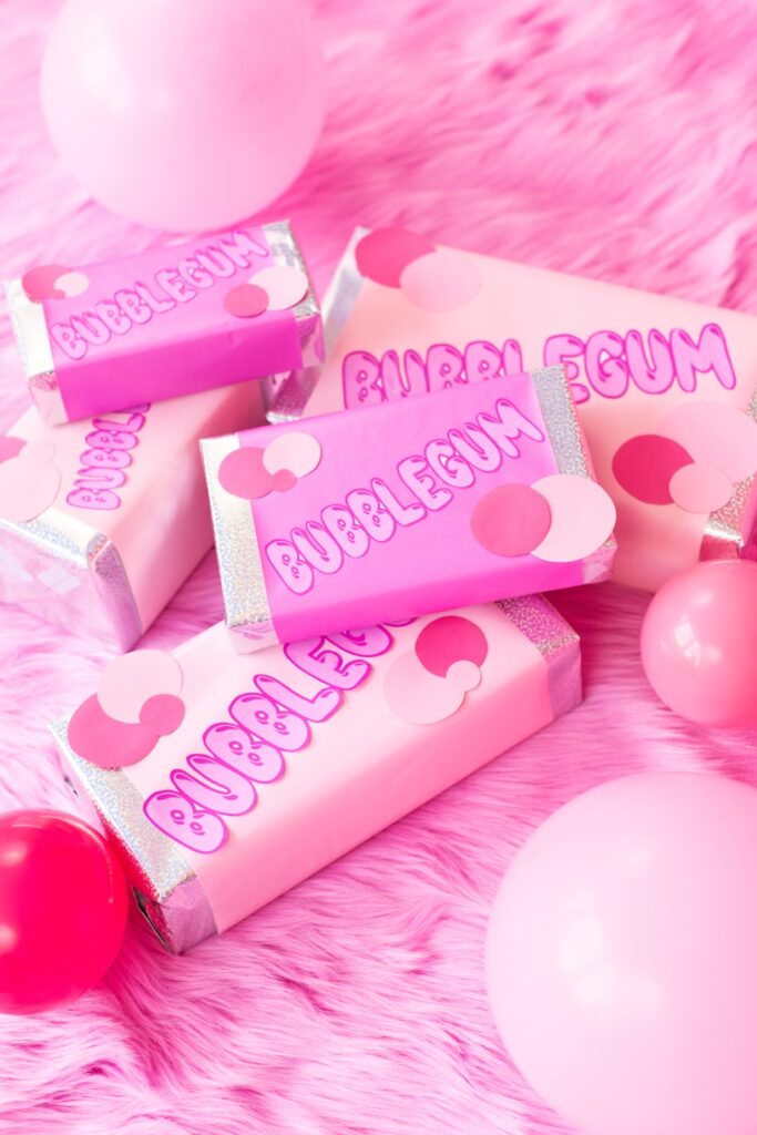 A gift box wrapped to resemble a bubblegum packet with vibrant pink details.