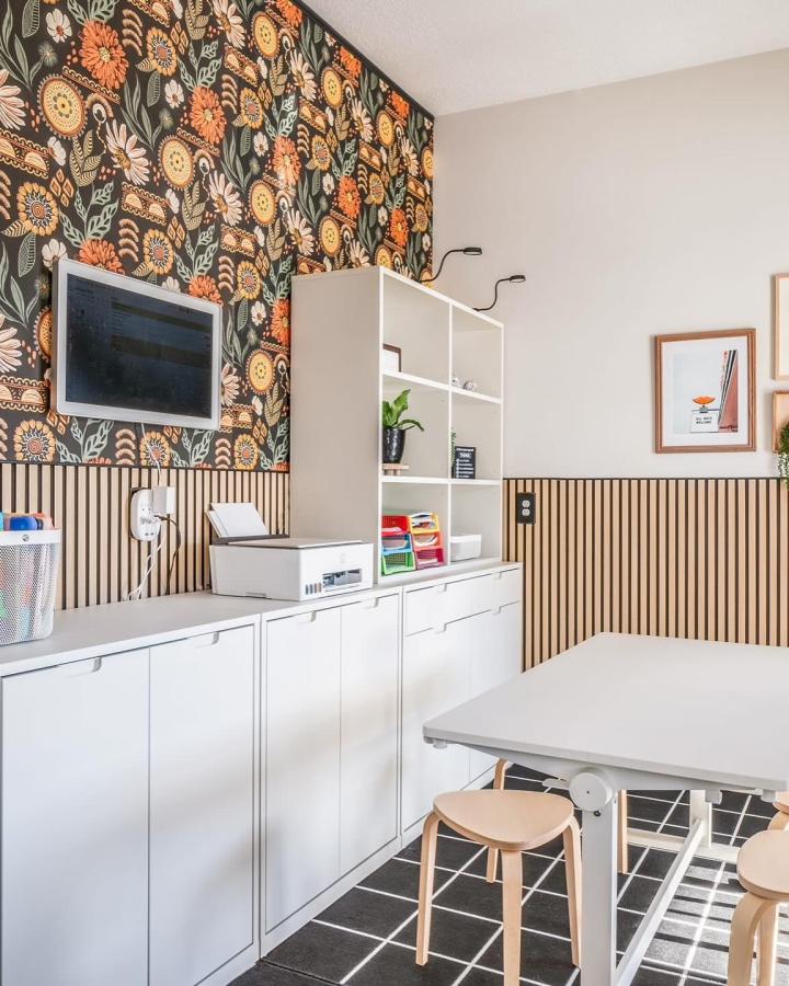 Floral wallpaper craft room from @mahoganydesignstudios. Bold orange and yellow blooms on dark green background.