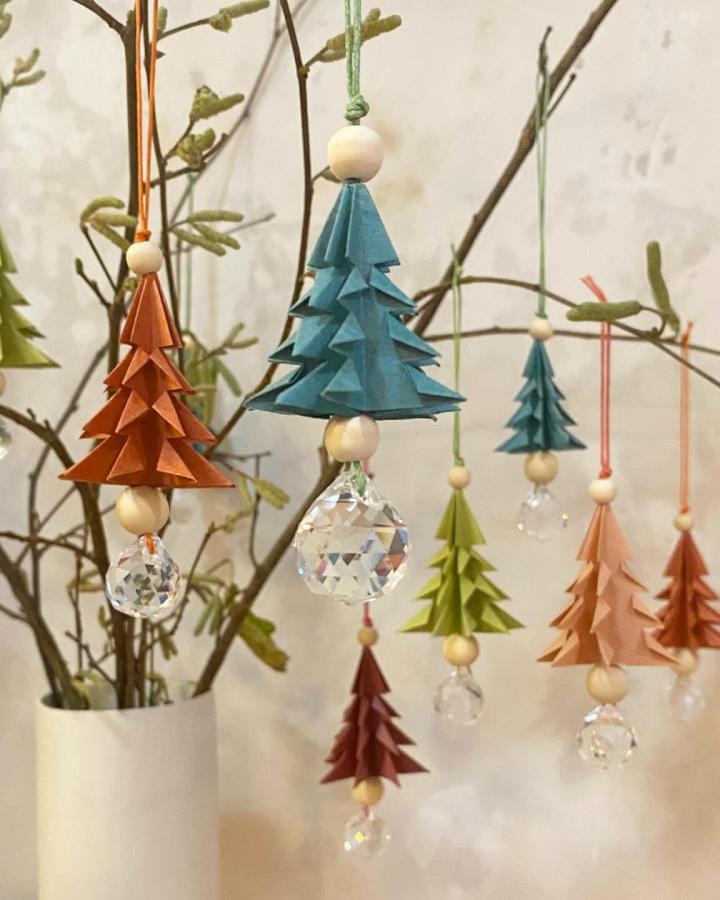 Origami tree ornaments with wooden beads and crystal drops from @eva_maria_berg hung on natural branches