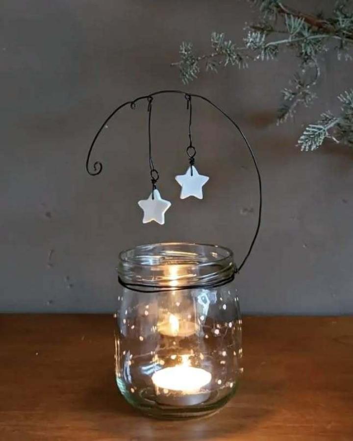 Wire star holder with mason jar candle display from @home2pepper featuring white ceramic ornaments and warm glow.