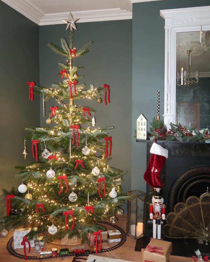 Red velvet bow decorated tree from @leannelimwalker with warm lighting and vintage ornaments displayed.