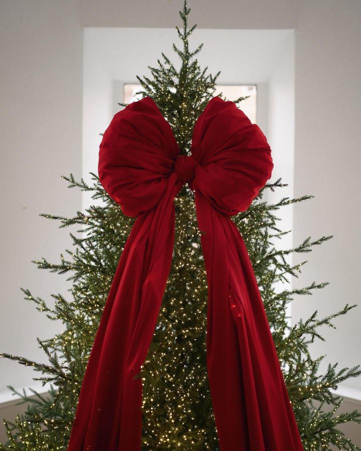 Dramatic red velvet tree topper from @flowerpower_moscow with cascading fabric tails and warm lights.
