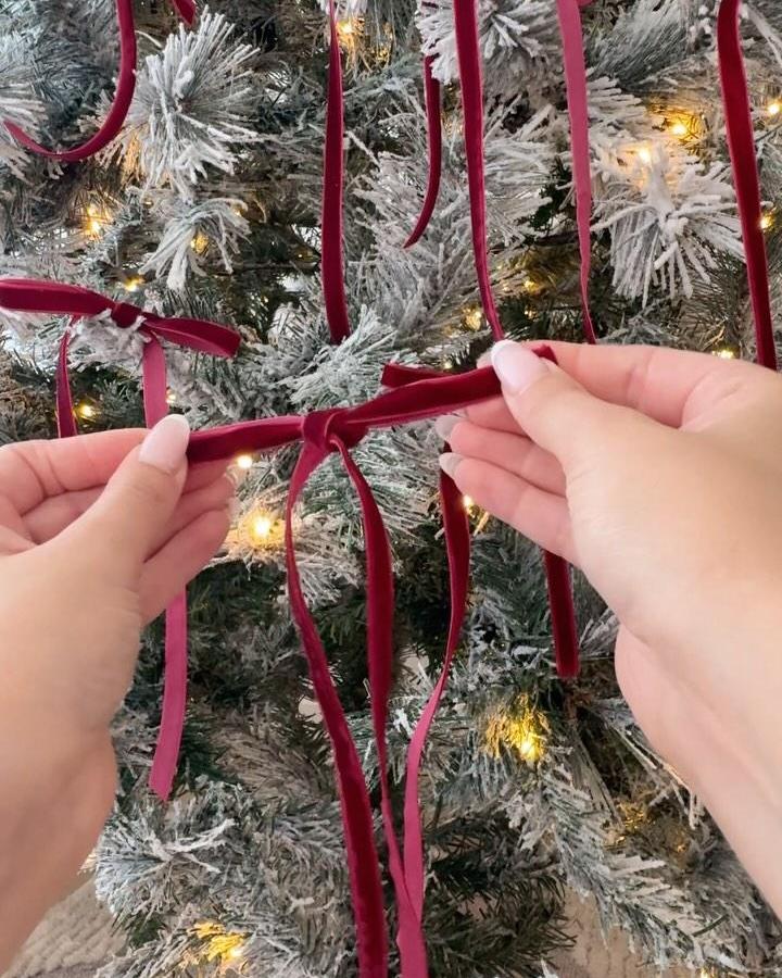 Burgundy velvet ribbons on flocked tree from @our.neutral.abode. Hands tying simple bows.