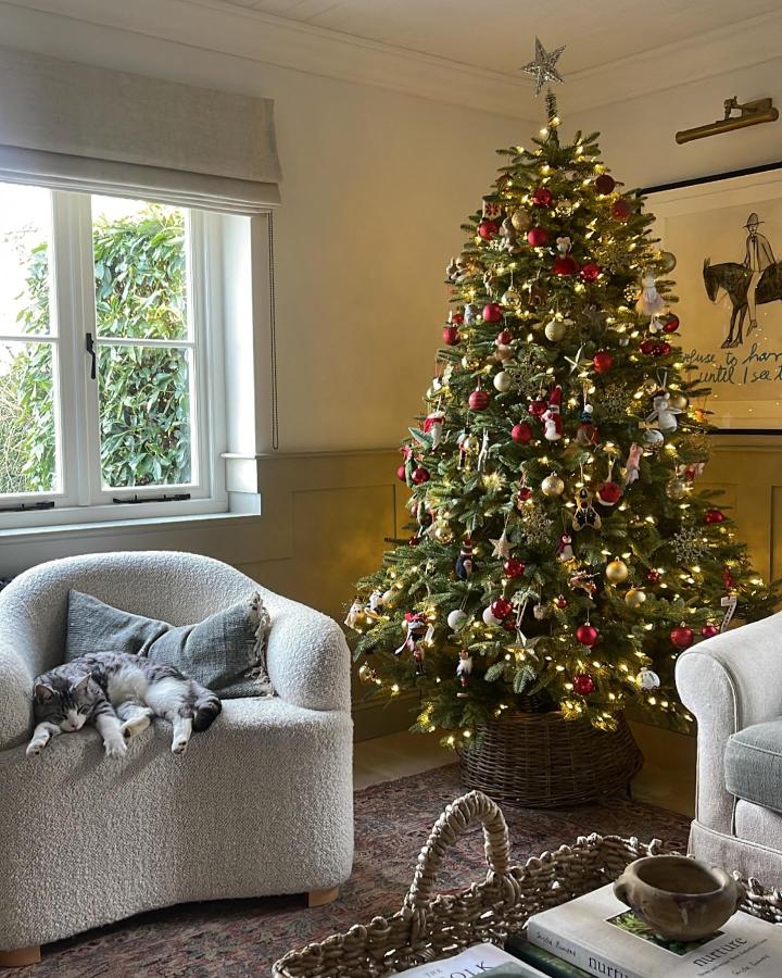 Dark woven basket tree base from @houseninecollections with festive ornaments and cozy living room setting