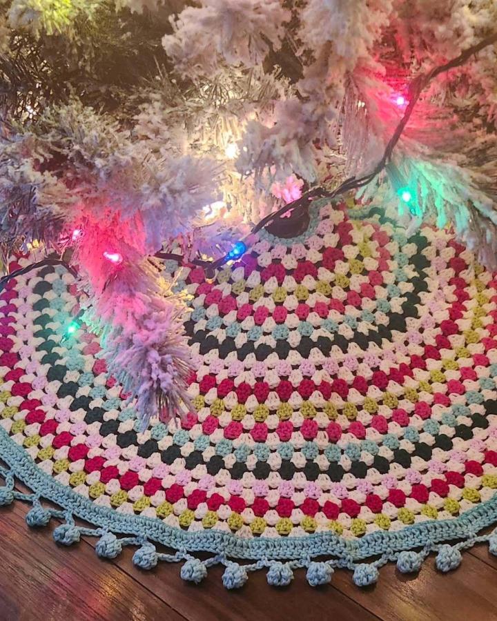 Colorful granny square crochet christmas tree skirt ideas from @amyunravelled with scalloped blue edge and multicolored stripes