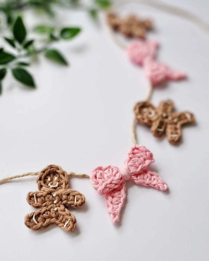 Pink and brown crochet christmas decorations ideas from @blossom.and.yarn featuring gingerbread garland on jute string with greenery.