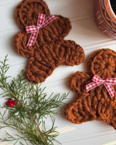 Brown textured gingerbread-shaped coasters from @blossom.and.yarn with red gingham ribbon bows and evergreen sprigs.