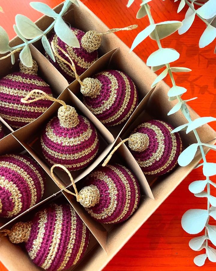 Purple and gold striped ornaments from @signe_elfriede stored in compartmented box with eucalyptus sprigs