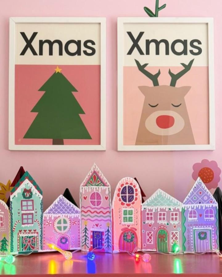 Painted shoebox village from @liddierowl with colorful houses and LED lights on pink background