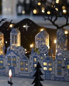 Blue and white patterned paper houses from @marenbaxter with illuminated windows and silhouette trees.