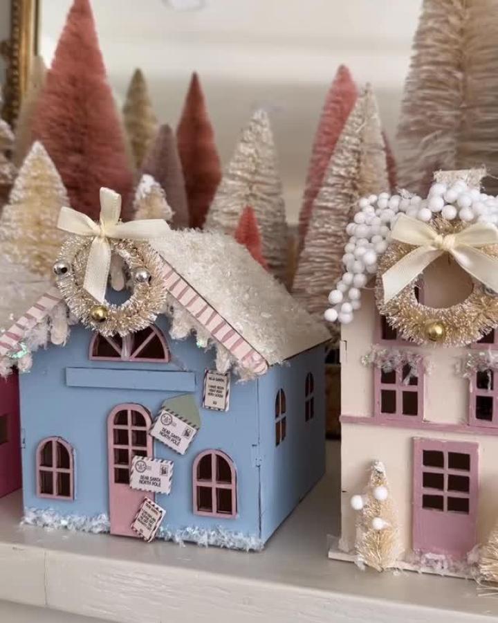 Pastel blue and pink miniature houses from @debtrette with gold tinsel wreaths and bottle brush trees.