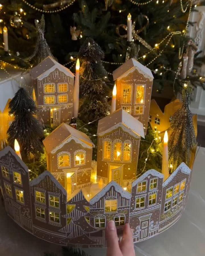 Illuminated paper houses with cut windows showcasing diy christmas village ideas from @marenbaxter. Warm LED lighting glows through intricate details.