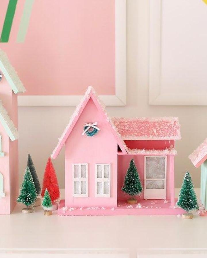 Pink cardstock miniature house from @annkelle featuring diy christmas village ideas with bottle brush trees and glitter accents.