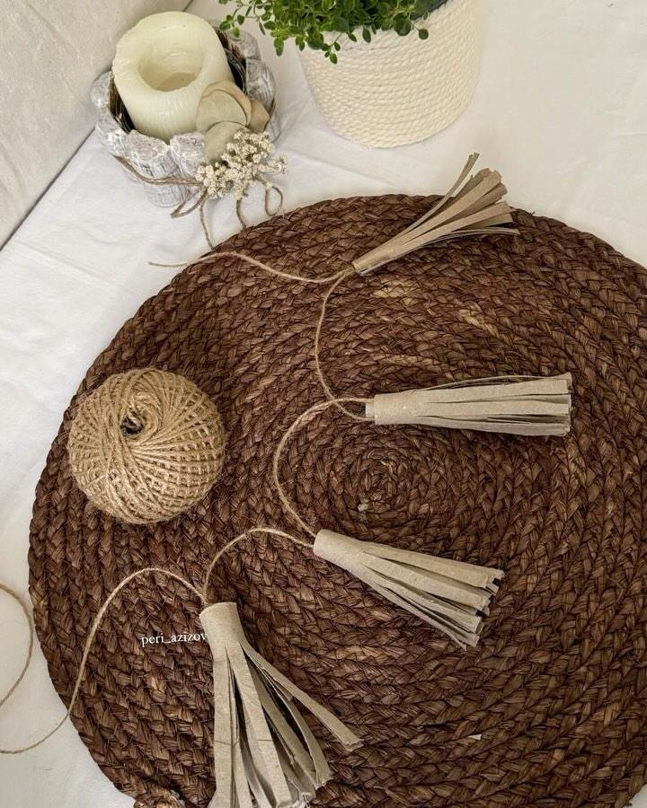 Neutral kraft paper tassel garland from @peri_azizov with jute twine and woven placemats as backdrop.