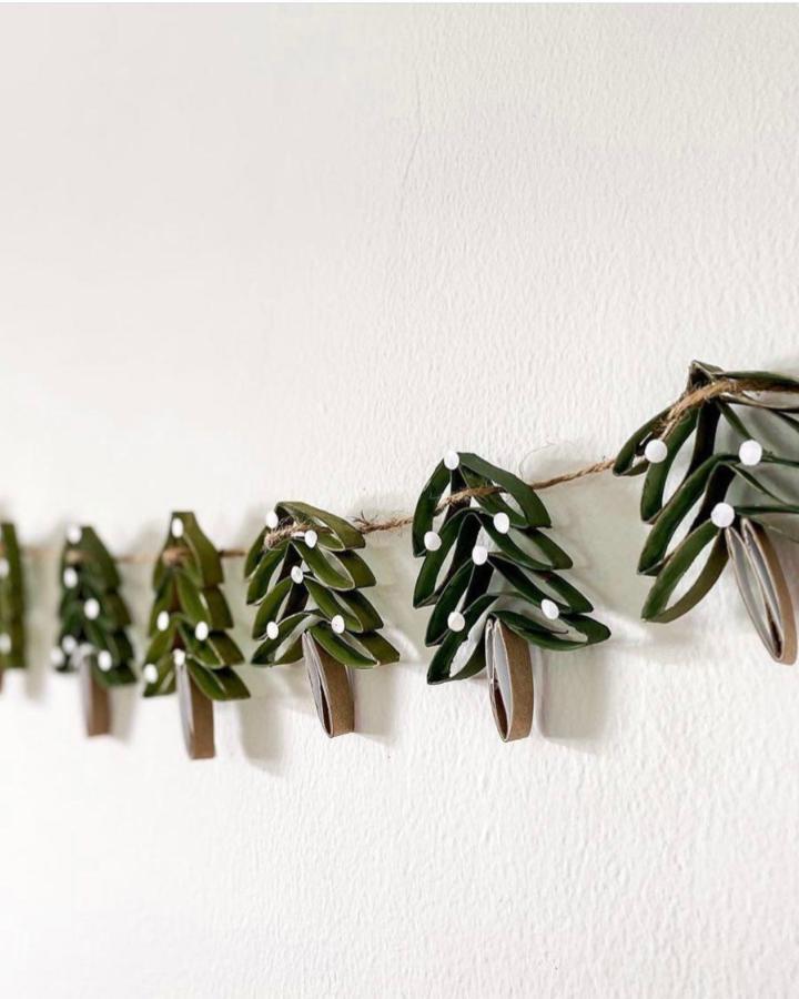 Cardboard pine tree diy paper garland ideas from @kimmyandbear with white dots and brown trunks strung on twine.