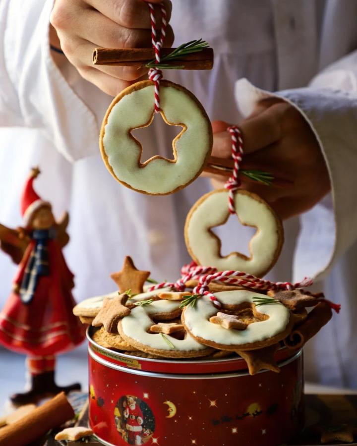 Pale green iced wreath cookies with cinnamon sticks from @homemade.is.happiness. Red striped twine and rosemary accents.