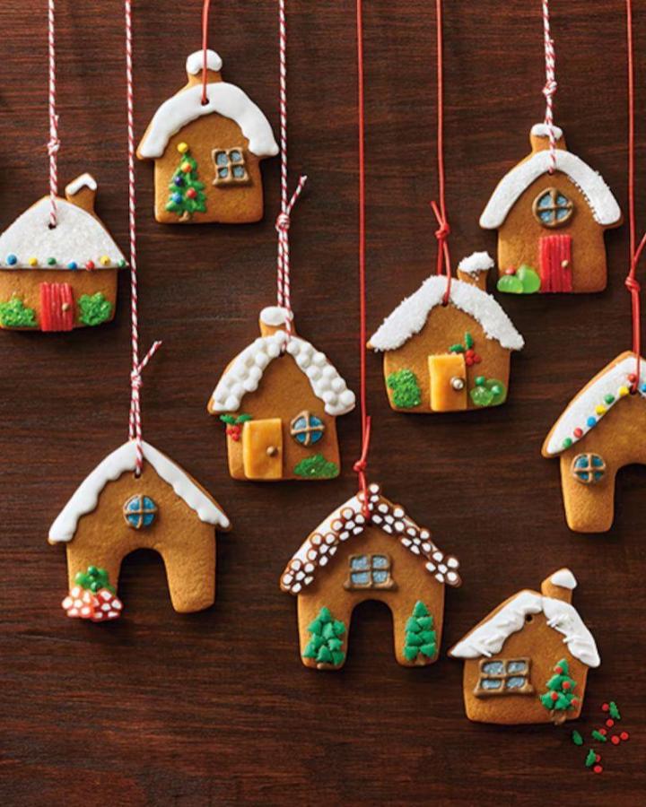 Hanging gingerbread christmas tree ornaments from @canadianliving. Miniature houses with colorful icing details on dark wood.