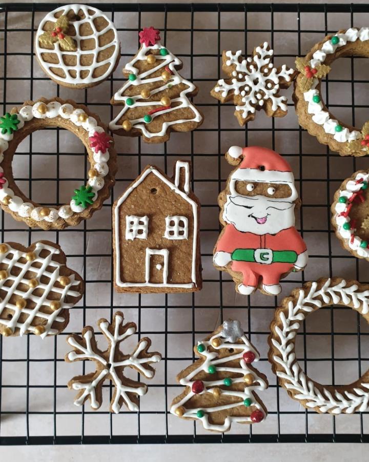 Assorted gingerbread cookies with white royal icing patterns from @gerrard_85 cooling on black wire rack