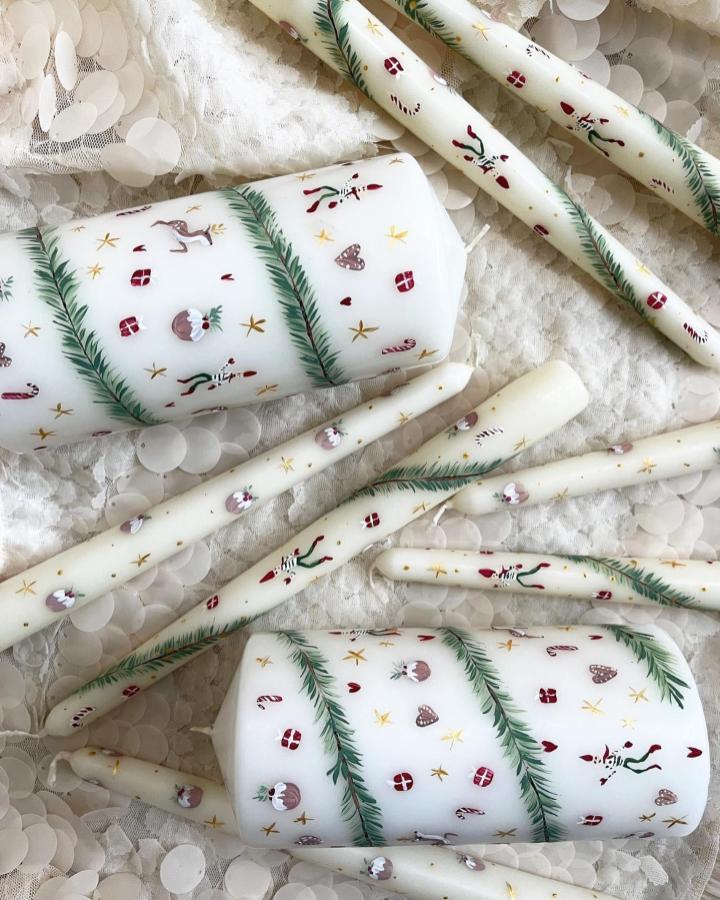 Wrapped pillar candles from @bougie_wax with festive printed paper and greenery accents displayed on lace