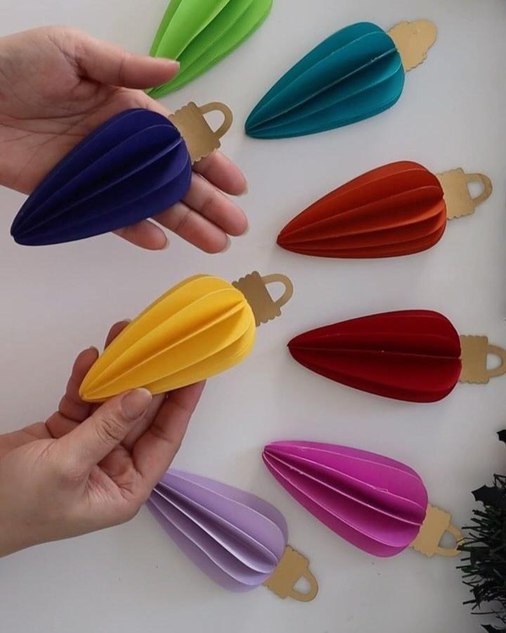 Multicolored accordion-folded paper ornaments from @tripta_crafts with kraft paper caps and hanging loops.