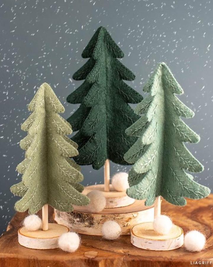 Felt evergreen tree trio from @liagriffith with embroidered branches on wood slice bases and white pom-poms