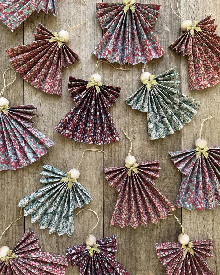 Floral patterned accordion folded paper angel ornaments from @melanielissackinteriors with wooden bead heads and gold ribbon details