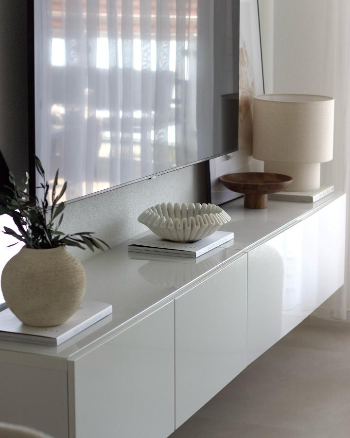 Floating white media console from @interior.caaat with sculptural decor and natural light.