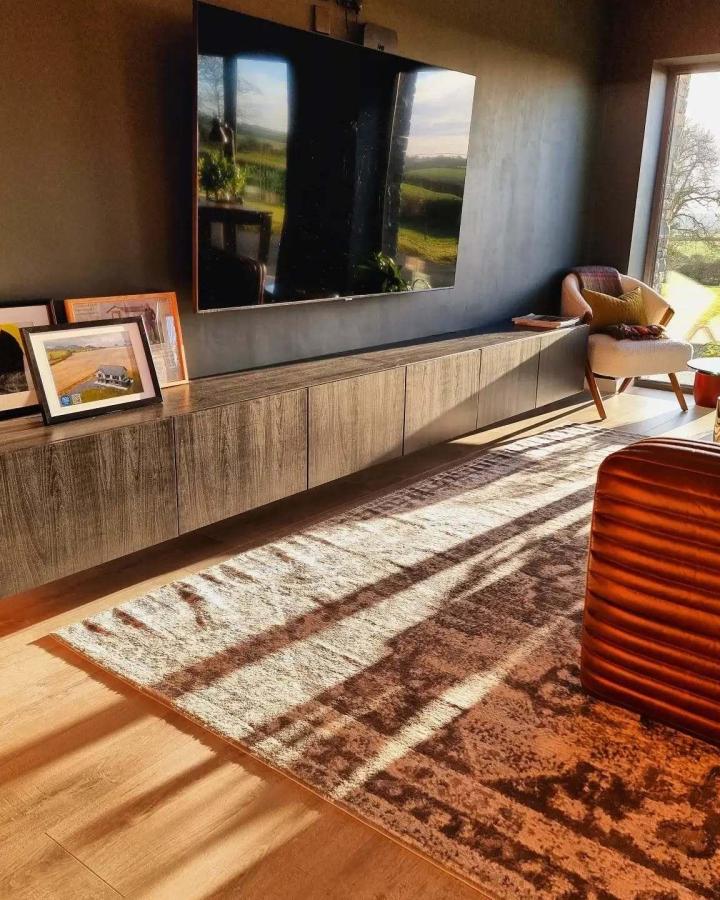 Pale oak floating media console from @passive_build with concrete accent wall and natural sunlight