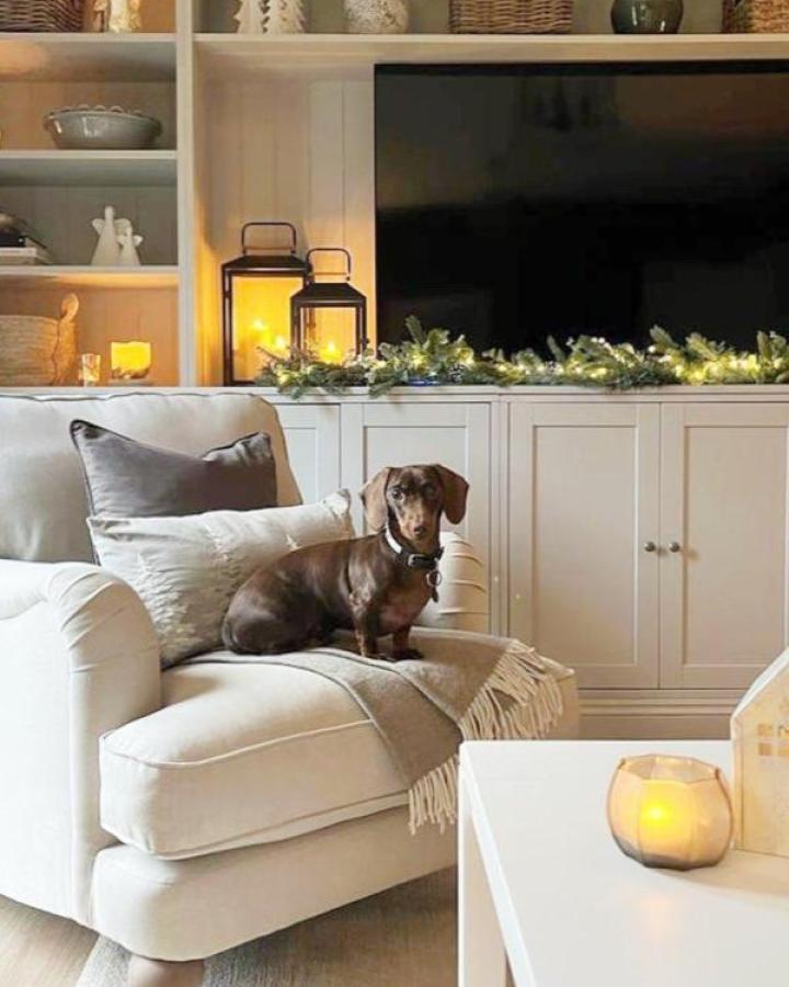 White media console from @grace.athome with seasonal greenery and lanterns beside mounted television.