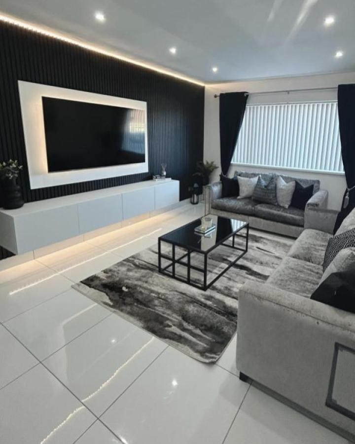 Black paneled living room from @nikishome18 featuring white Besta cabinets with backlit LED strips and framed TV.
