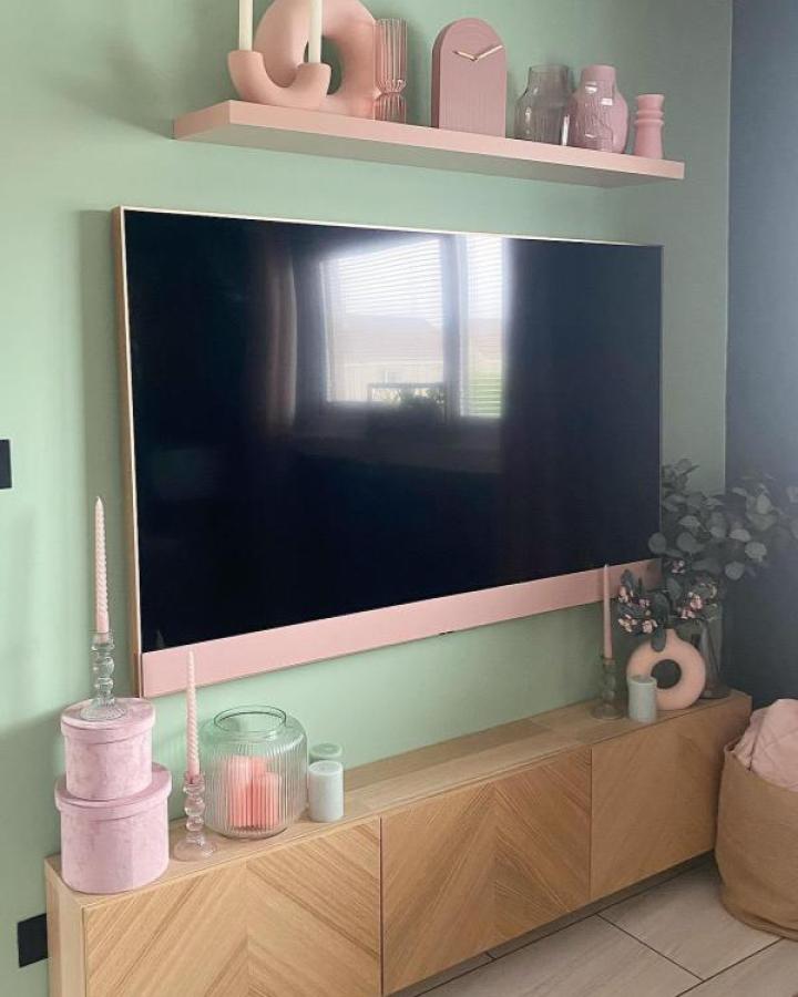 Mint green wall with oak media console from @the_gaygordons featuring pink floating shelves and decorative accents.