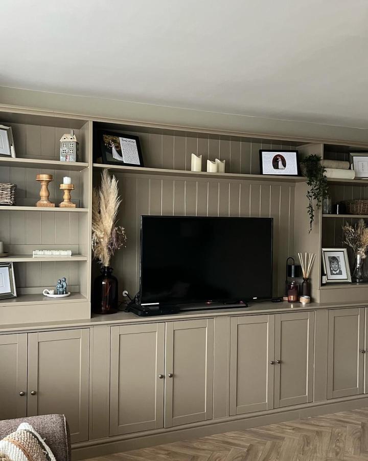 Sage green paneled media wall from @turner_no13_home. Built-in shelving with natural decor accents.