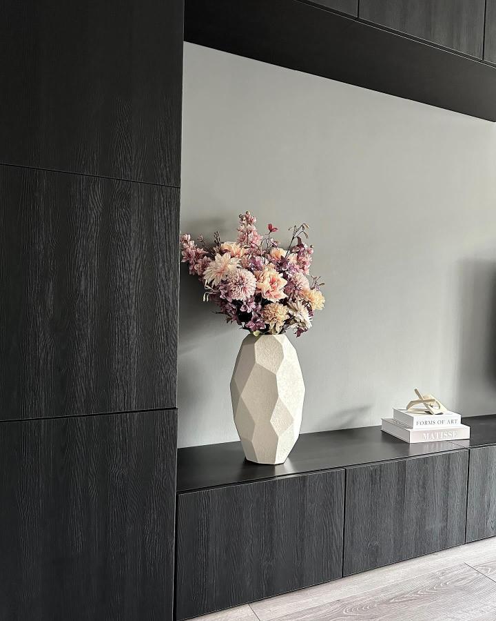 Dark wood grain media console from @interior_by_klaudia with geometric vase and pink florals displayed.