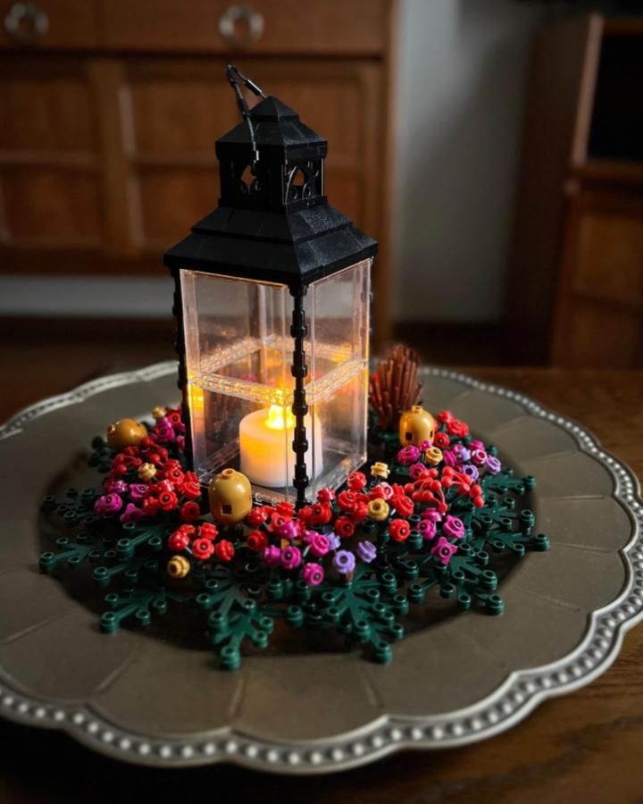 Black lantern centerpiece with lego christmas decorations wreath base from @umemaruko7. Colorful ornaments surround flameless candle.