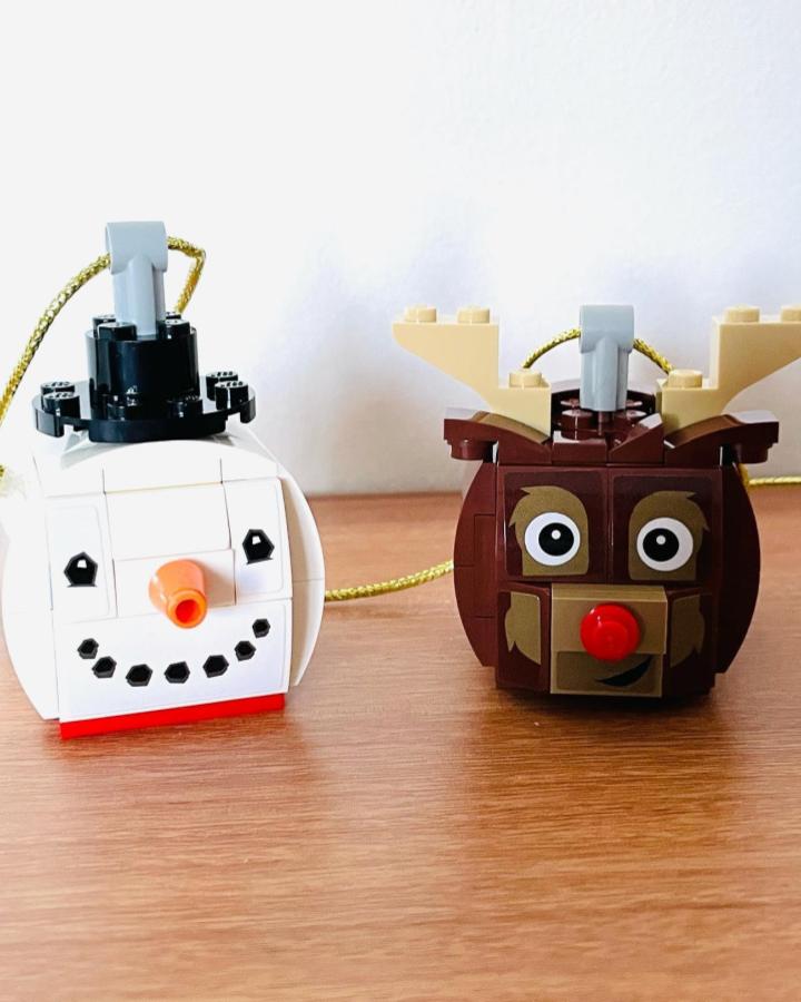 White snowman and brown reindeer brick ornaments from @timbuckle81 with gold hanging cords on wood surface