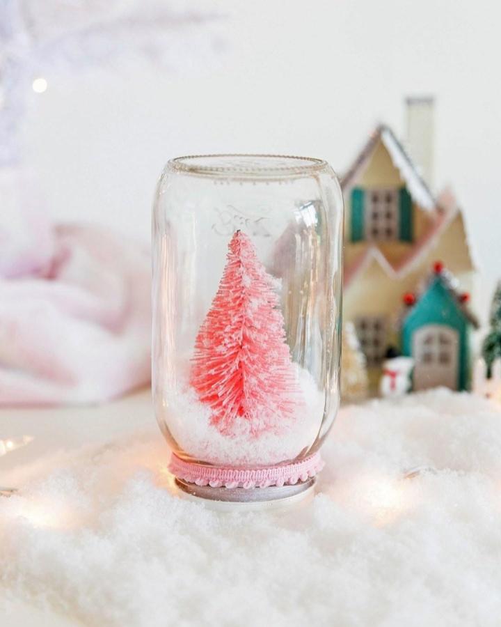 Pink bottle brush tree snow globe craft from @betterhomesandgardens with miniature village backdrop and pearled trim detail.