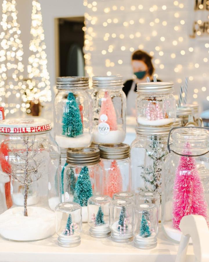 Colorful bottle brush tree display from @masonjarmerchant featuring teal, pink, and white miniature winter scenes in jars.
