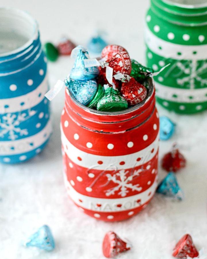 Painted sweater-pattern jars from It All Started with Paint filled with festive wrapped candies.