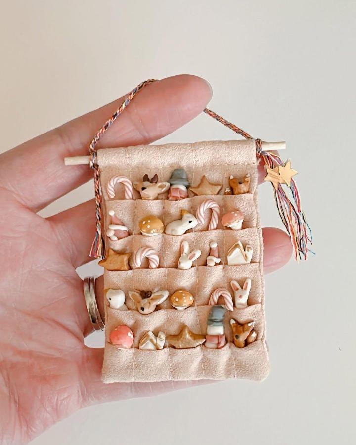 Tan felt pocket organizer from @buffaloandbubblegum with miniature woodland ornaments and candy canes displayed inside.