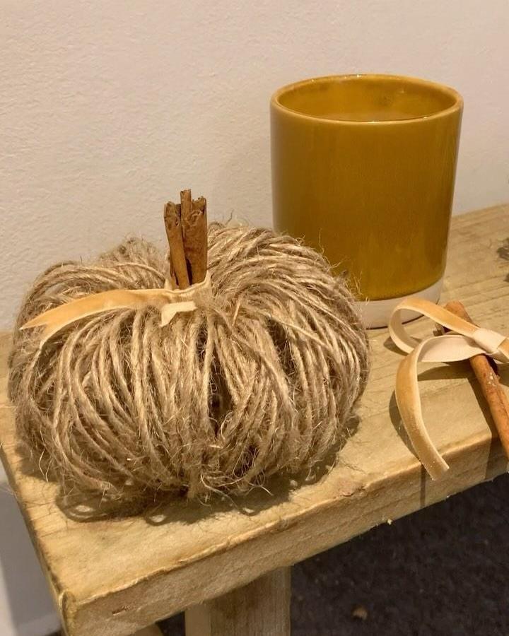 Jute-wrapped pumpkin craft from @thepomwreathcompany. Cinnamon stick stem and ribbon detail on wood surface.