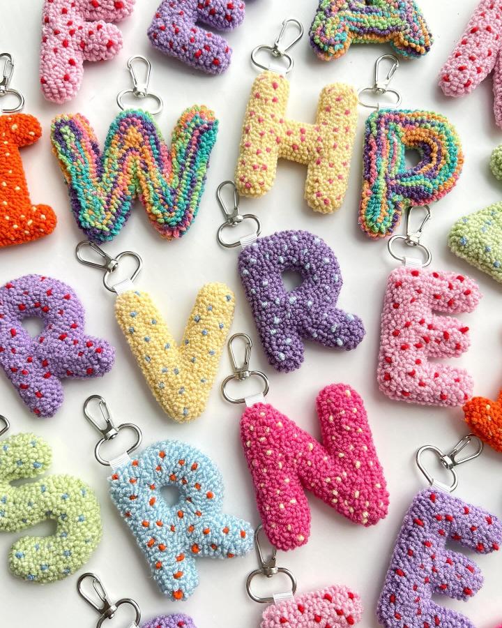 Colorful letter keychains from @embroiderywithaycan with textured yarn and silver clasps in varied hues