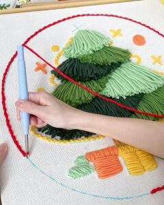 Layered green yarn punch needle christmas decorations from @craftsuki.id. Hand working textured tree with colorful accents.