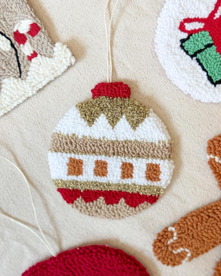 White and gold striped ornament from @punch.zey with red crown detail and geometric pattern.