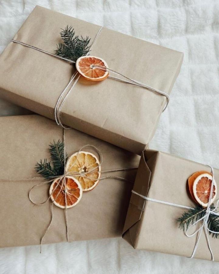 Kraft paper gift wrap with dried citrus and greenery from @soulgrown_alabama. Natural twine secures rustic holiday accents.