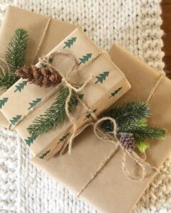 Kraft paper gifts with stamped green trees from @built.on.love, tied with jute and natural greenery.