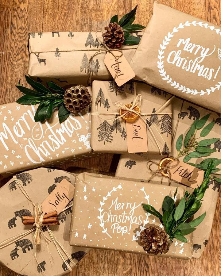 Kraft paper packages with stamped woodland animals from @inbloom.and.co. Natural embellishments including pinecones and greenery.