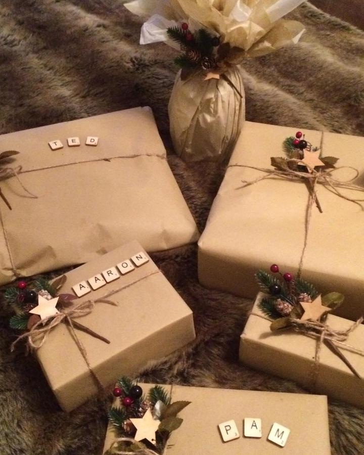 Rustic brown paper christmas wrapping ideas from @kerrymac2010 featuring scrabble tiles, jute twine, and festive greenery accents.