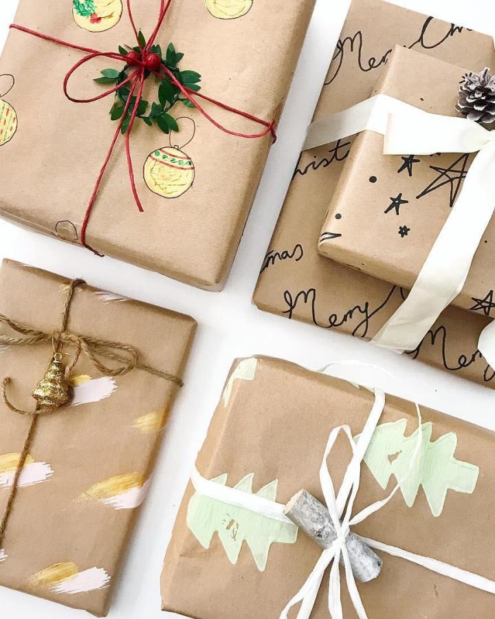 Hand-painted ornament designs on kraft paper gift wrap from @bangonstyle with festive ribbon and wreath charm.