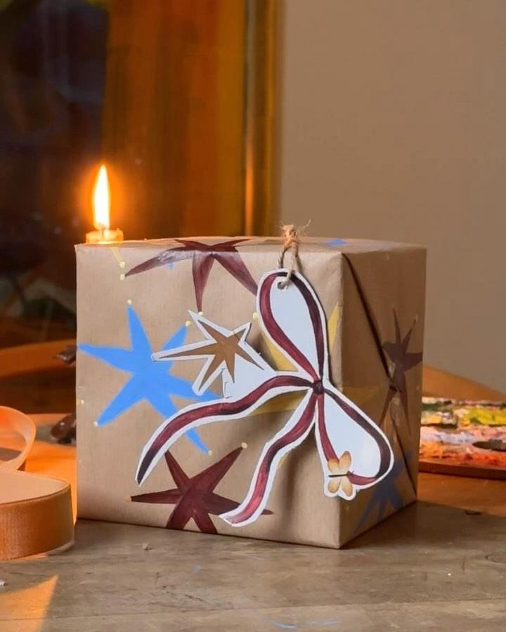 Hand-painted brown paper christmas wrapping ideas from @roseenglandlondon featuring dove and starburst motifs in burgundy and blue.